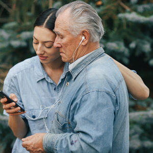 Woman listening music with an elderly man off of a smartphone