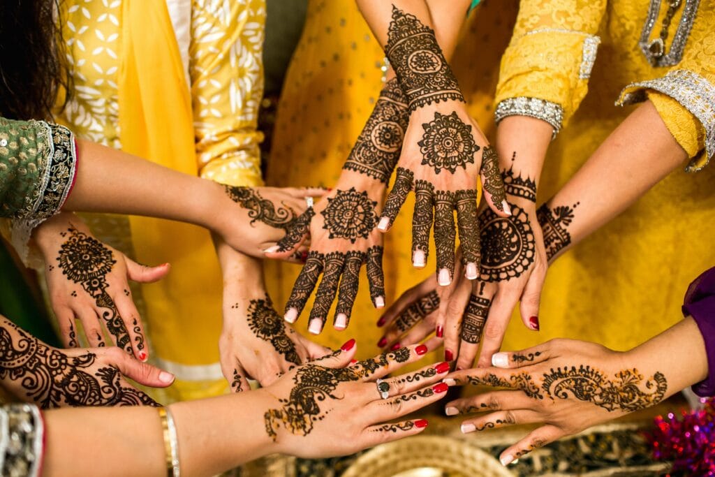 Several girls sit together, their hands adorned with intricate henna designs. Henna, a temporary body art form, is used to create decorative patterns on the skin. It is often used for celebrations and special occasions, such as weddings or festivals, in various cultures around the world.