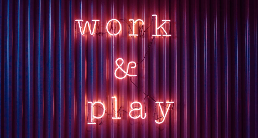 Neon sign on a wall that reads "work & play"