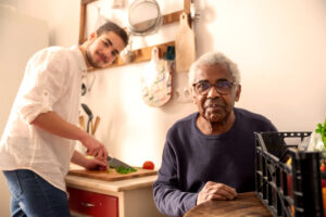 A support worker helping an elderly man prepare his dinner